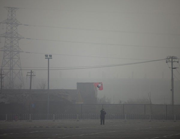 Homem solta pipa em Pequim, onde poluição em nível alarmante encobriu o céu nste sábado (12) (Foto: Alexander F. Yuan/AP Photo)