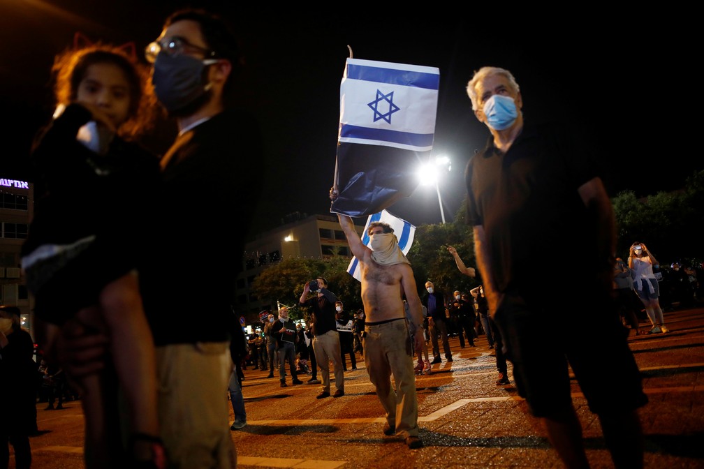 Com máscaras, manifestantes protestam contra primeiro-ministro de Israel, Benjamin Netanuyahu, em Tel Aviv neste domingo (19) — Foto: Corinna Kern/Reuters