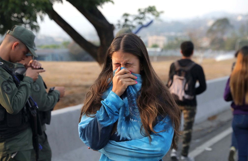 Mulher cobre o rosto após respirar gás lacrimogêneo atirado por militares da base aérea 'La Carlota', em Caracas — Foto: Manaure Quintero/Reuters