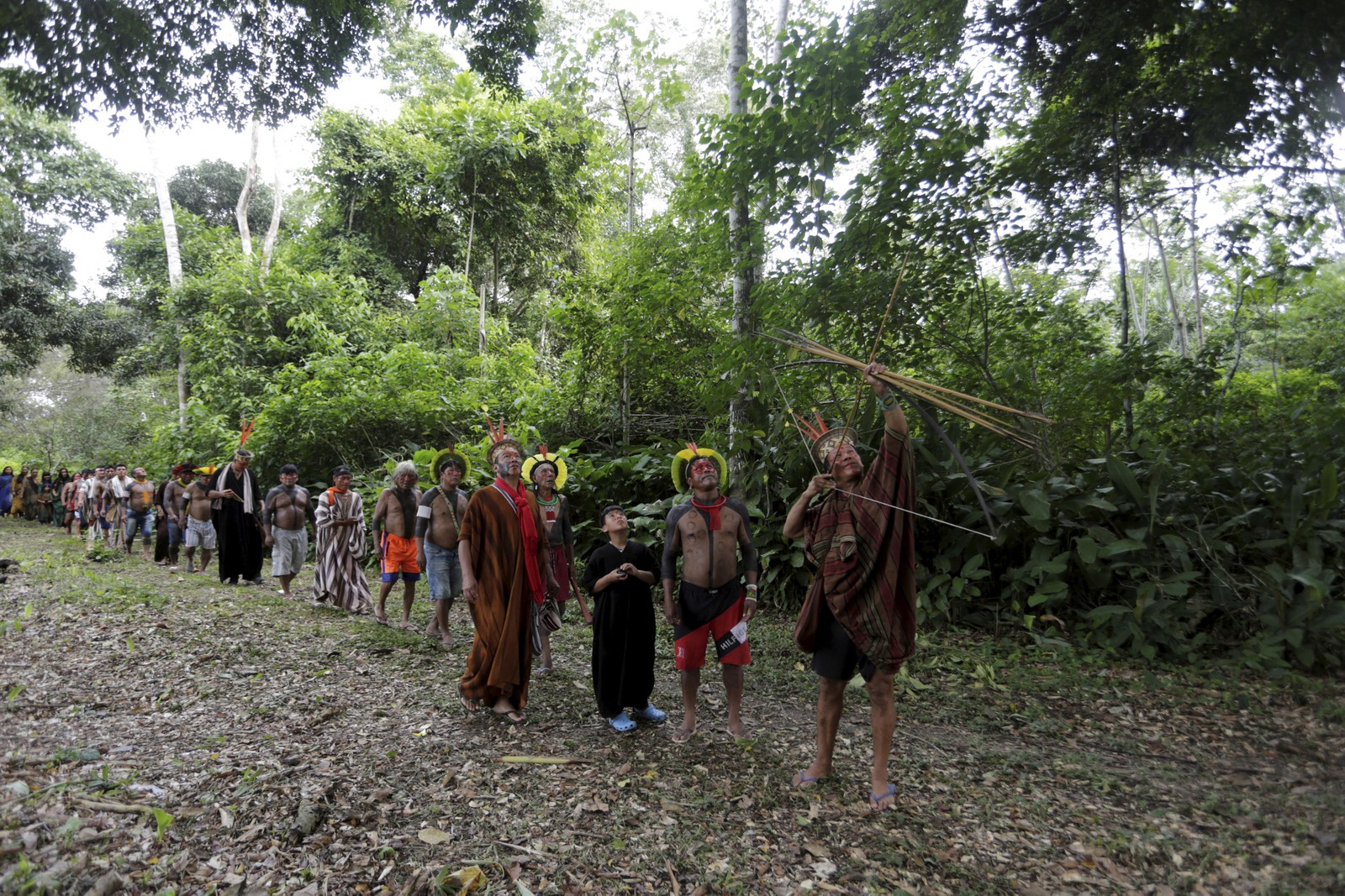 Indígenas kayapós observam o líder espiritual e guerreiro ashaninka, Moisés Pyãko, que prepara seu arco e flecha em busca de caça na floresta  — Foto: Domingos Peixoto / Agência O Globo