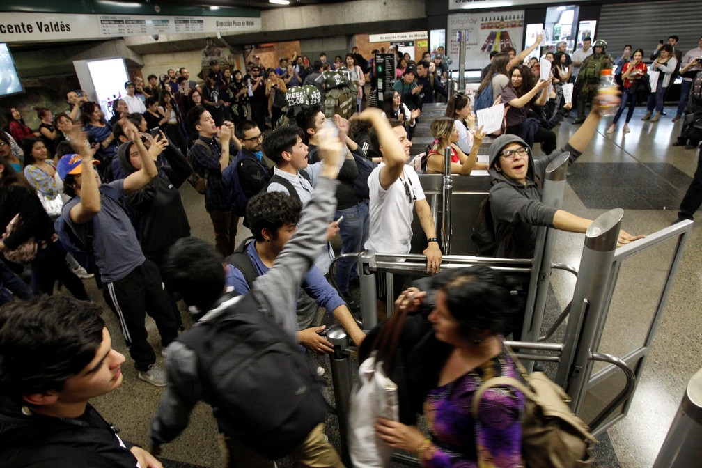 Manifestantes pulam catraca em estação de metrô durante protesto contra aumento da tarifa de transporte pública em Santiago, no Chile, na sexta-feira (18) — Foto: Reuters/Carlos Vera