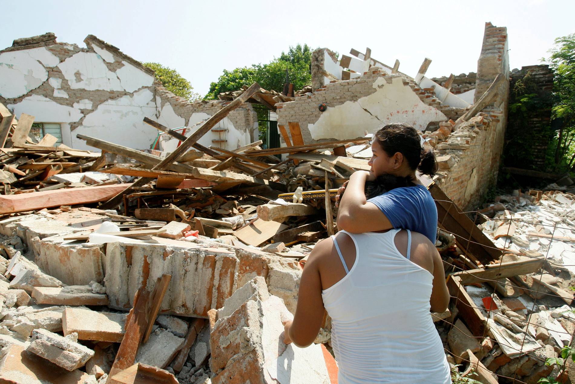 Mulheres se abraçam ao lado de uma casa destruída após terremoto, em Union Hidalgo, no México