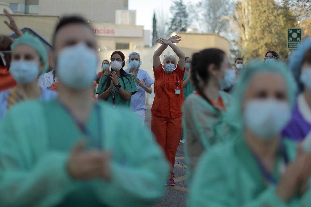 Profissionais da saúde recebem aplausos em hospital e retribuem as palmas em Madri, na Espanha — Foto: Manu Fernandez/AP Photo