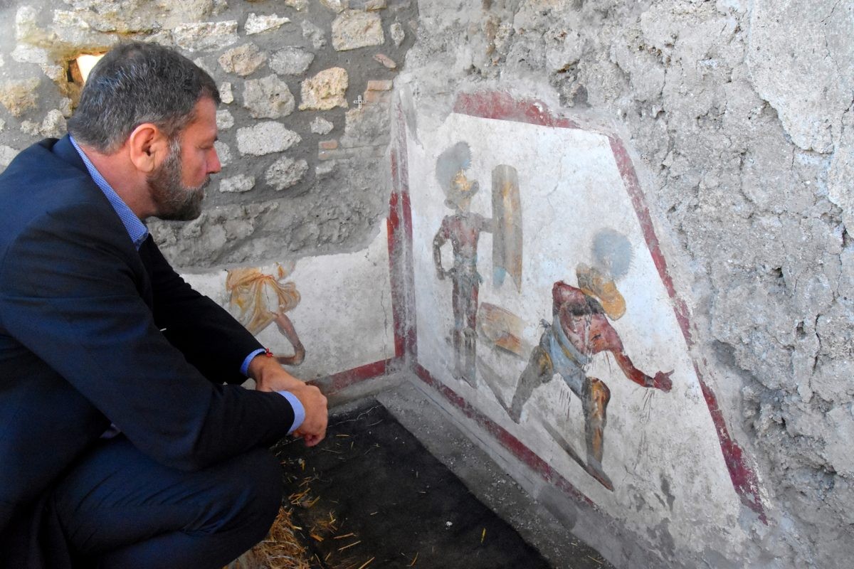 Massimo Osanna observa o afresco. Ao lado, outro registro está sendo escavado por arqueólogos (Foto: Reprodução Parco Archeologico di Pompei)