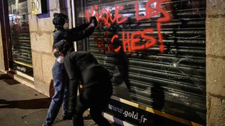 Manifestantes picham a vitrine de uma loja durante protestos contra a reforma da Previdência, em em Nantes — Foto: LOIC VENANCE / AFP