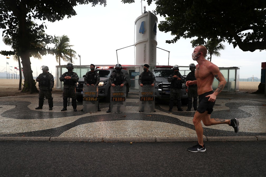 Homem corre na praia de Copacabana, no Rio de Janeiro, em frente a posto vigiado por policiais no domingo (7), dia de manifestações contra e a favor do governo — Foto: Pilar Olivares/Reuters