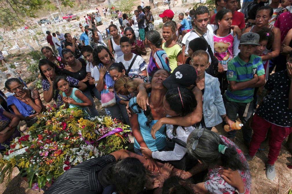 Parentes se emocionam durante enterro de detento morto em incÃªndio em prisÃ£o na cidade de ValÃªncia, na Venezuela (Foto: Juan Carlos Hernandez/AFP)