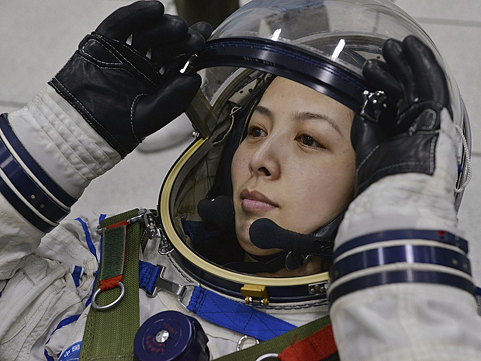 Astronauta chinesa Wang Yaping ajusta o capacete espacial durante treinamento em Pequim em 2013. — Foto: Reuters