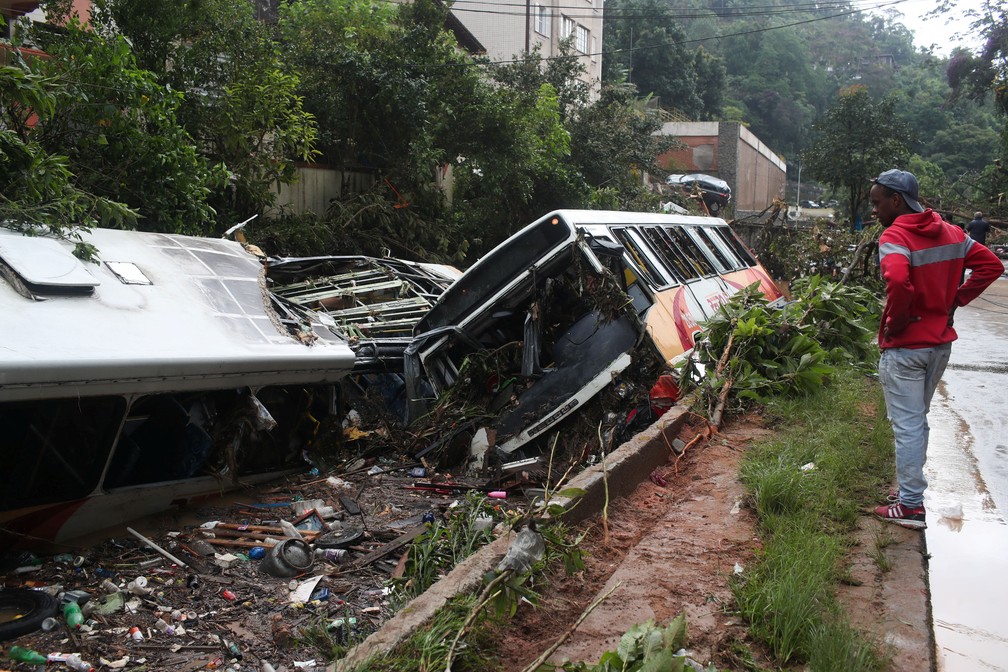 Um homem observa dois ônibus destruídos após temporal em Petrópolis (RJ) — Foto: Ricardo Moraes/Reuters