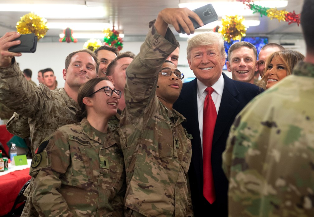 O presidente dos EUA Donald Trump e a primeira-dama Melania Trump tiram uma selfie com militares dos EUA durante uma viagem não anunciada à Base Aérea de Al Asad, no Iraque, em 26 de dezembro de 2018  — Foto: Saul Loeb/AFP/Arquivo