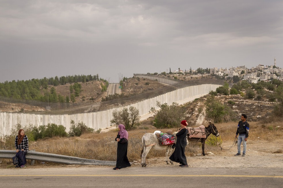 Palestinos esperam autorização de soldados isralenses para cruzar fronteira bloqueada na Cisjordânia ocupada, em 26 de outubro de 2022. — Foto: Oded Balilty/ AP