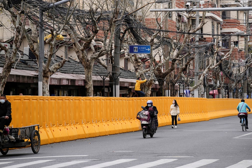 Pessoas e veículos nas ruas de Shangai, na China. Muro separa a rua das casas e edifícios — Foto: Aly Song/Reuters