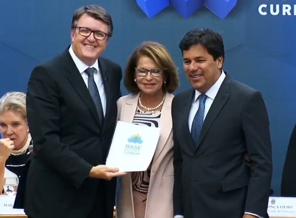 Eduardo Deschamps (esq.), presidente do CNE, recebe a última versão da BNCC das mãos da secretaria-executiva do MEC, Maria Helena Guimarães (centro) e do ministro da Educação, Mendonça Filho (dir.) (Foto: Reprodução/Facebook)