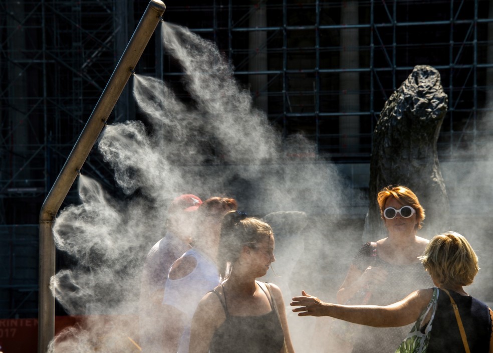 Mulheres se refrescam com borrifador de água público em Lille, na França, durante onda de calor na Europa (Foto: Philippe Huguen/AFP)