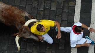Participantes fogem de touro pelas ruas de Pomplona, Espanha — Foto: ANDER GILLENEA / AFP