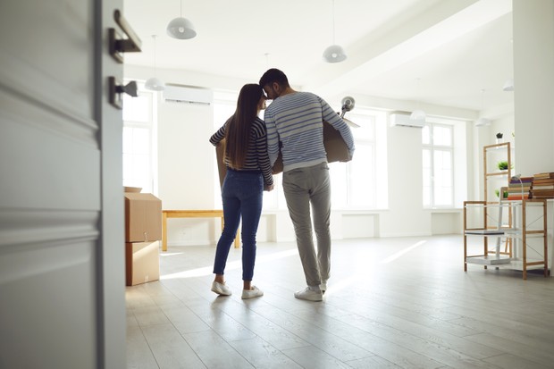 Rear view moving. Young couple family with boxes to move in a new house room. Buying sale, rent, real estate mortgage. (Foto: Getty Images/iStockphoto)