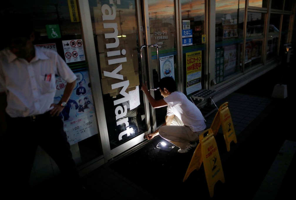 Homem usa lanterna para fechar loja nesta segunda-feira (9) durante blecaute provocado pelo tufÃ£o Faxai em Kisarazu, na provÃ­ncia de Chiba  â?? Foto: Issei Kato/ Reuters