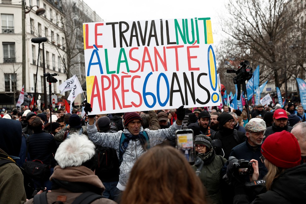 Manifestante segura cartaz com a mensagem 'o trabalho faz mal para a saúde após os 60 anos' durante protesto contra a reforma das pensões do governo francês, em Paris, em 19 de janeiro de 2023. — Foto: Benoit Tessier/ Reuters