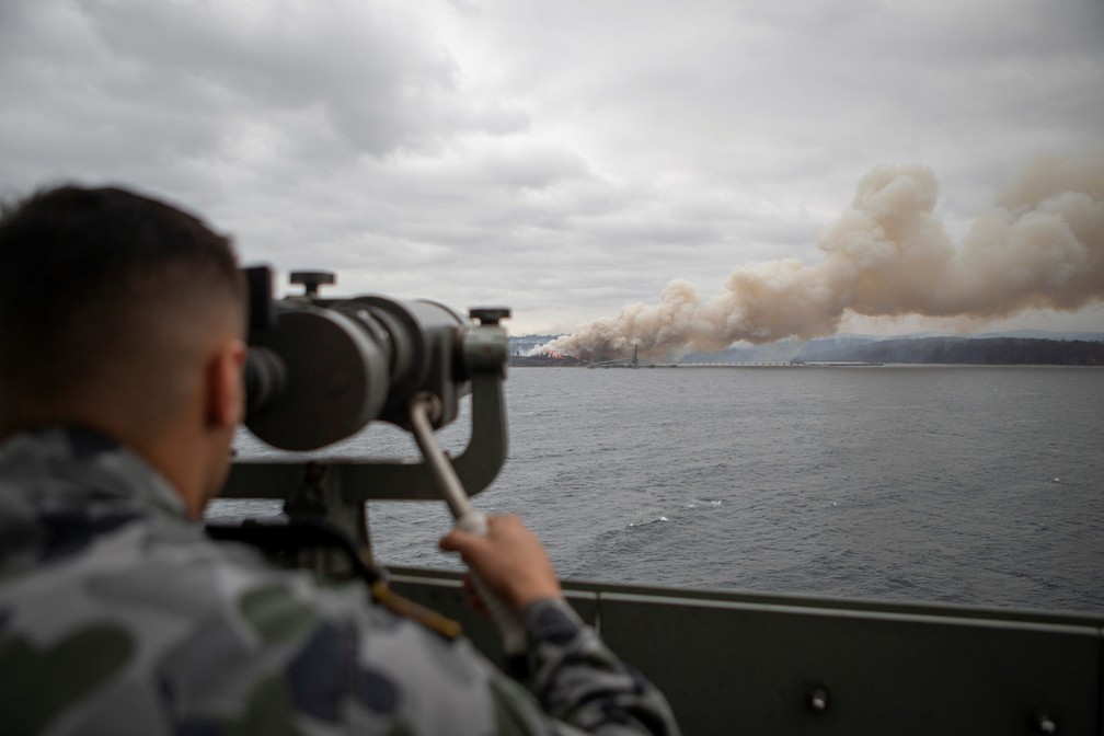 5 de janeiro - O marinheiro Boatswains Malik El-Leissy observa um incêndio em chamas durante a chegada do navio a Eden, na Austrália, na operação Bushfire Assist 2020 — Foto: Thomas Sawtell/Departamento de Defesa da Austrália/Divulgação via Reuters