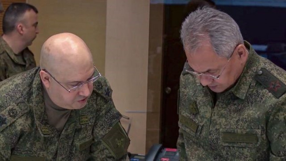 O general Surovikin (esq.) disse que a retirada, ordenada pelo ministro da Defesa (dir,) foi uma decisão difícil — Foto: MINISTÉRIO DA DEFESA DA RÚSSIA