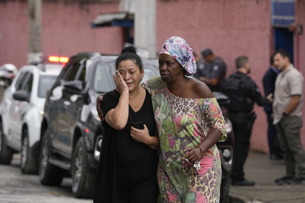Silvia Palmieri, mãe de uma professora que sobreviveu a um atentado a facadas na escola Thomazia Montoro, sai da escola consolada por uma amiga — Foto: Andre Penner/AP