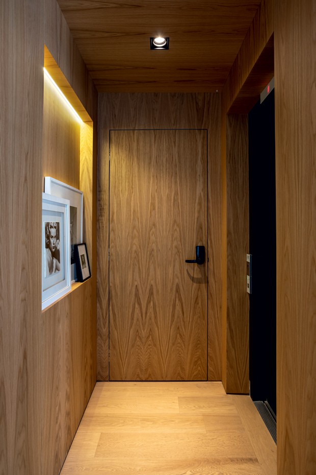 O hall do elevador tem porta e paredes revestidas de tauari albanizado (Foto: Fran Parente / Divulgação)
