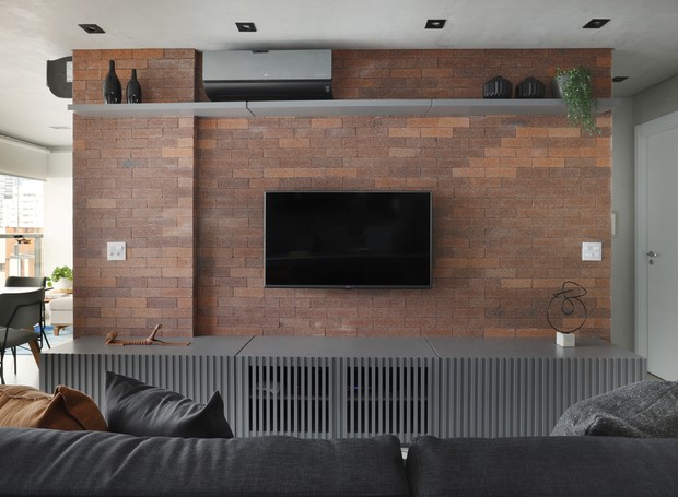Sala de tv | Para aquecer o ambiente, a arquiteta Gabrielle Fuzinato criou uma parede de tijolinhos da Palimanam, que faz as vezes de painel de tv  (Foto: Mariana Orsi/Divulgação)