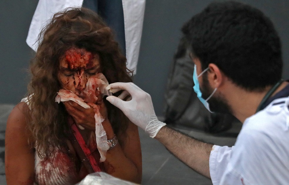 Enfermeiro cuida de mulher ferida em explosão na zona portuária de Beirute, no Líbano — Foto: IBRAHIM AMRO/AFP