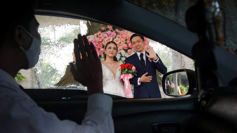 29 de junho - Convidado dentro de um carro acena para a noiva e o noivo durante cerimônia de casamento que implementa medidas de distanciamento social, em Tangerang, na Indonésia — Foto: Fajrin Raharjo/AFP