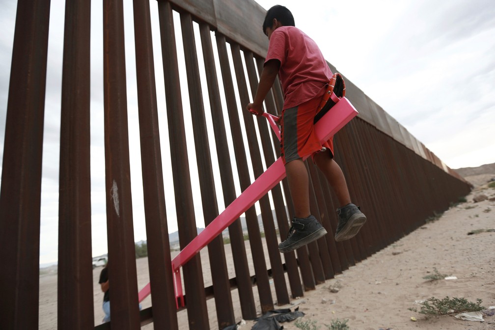 Uma criança brinca em uma gangorra instalada na cerca que divide a fronteira entre o México e os EUA em Ciudad de Juarez — Foto: Christian Chavez/Reuters
