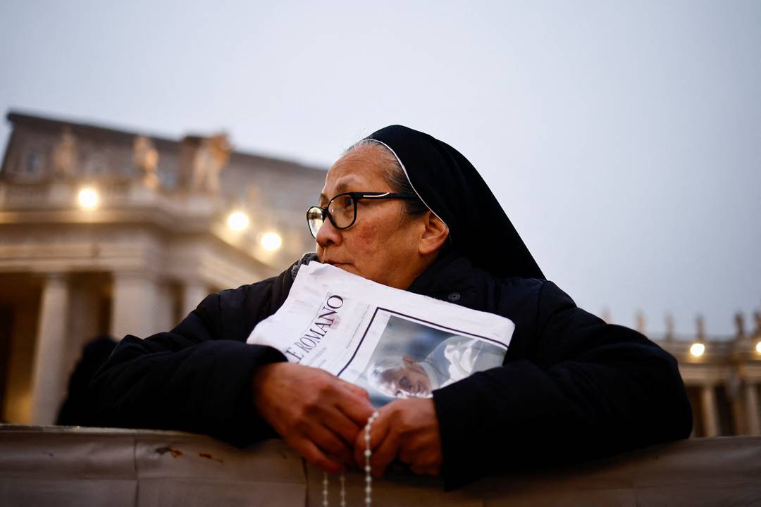 Freira segura um exemplar do jornal 'L'Osservatore Romano' enquanto espera na Praça de São Pedro pelo funeral de Bento XVI 