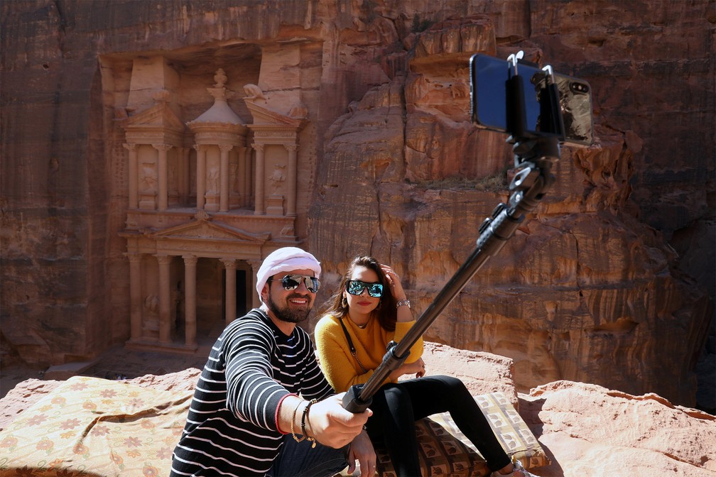 Casal de turistas posa para selfie diante do portal da cidade de Petra, ao sul de Amã, na Jordânia — Foto: Muhammad Hamed/Reuters
