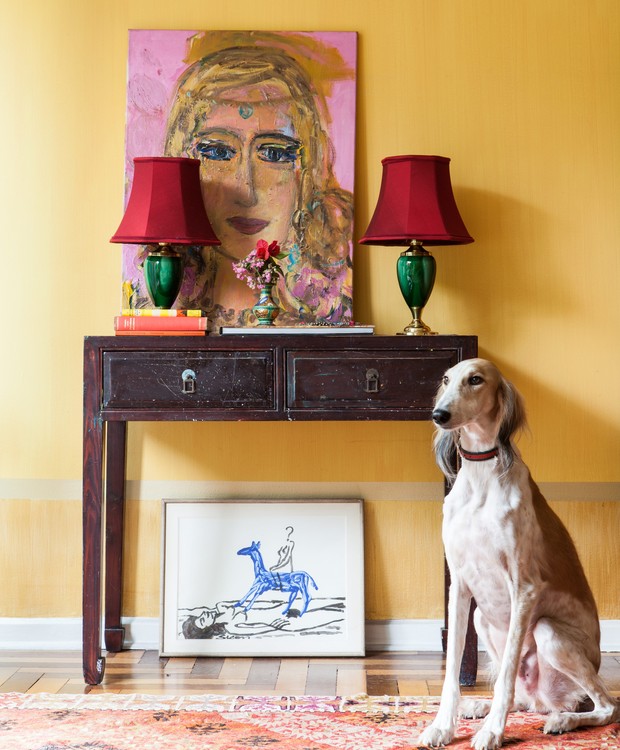 Sala da pintora Verena Matzen, com parede amarela, aparador de madeira da L'Oeil, abajur da Saulo Cúpulas, tela com seu auto-retrato, e seu cachorro galgo, Sheik. São Paulo (Foto: Lufe Gomes / Editora Globo)