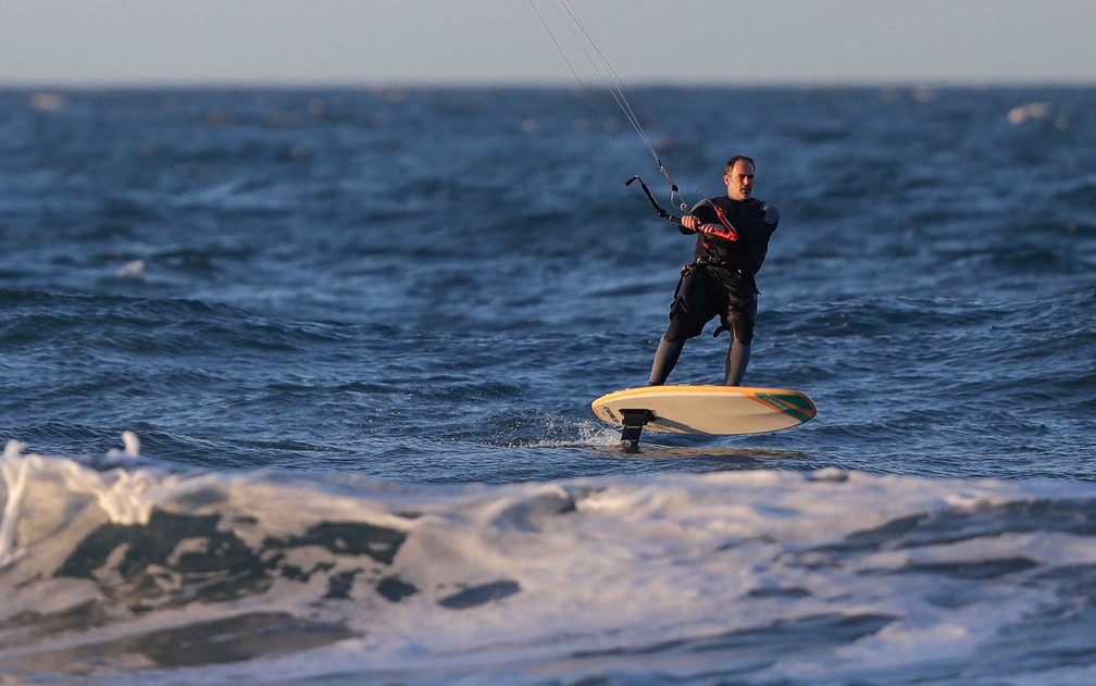 Homem pratica windsurf em New Brighton Beach, em Christchurch, na Nova Zelândia, no primeiro dia após o fim das regulamentações depois de o país ser declarado livre do coronavírus, na terça-feira (9) — Foto: AP Photo/Mark Baker