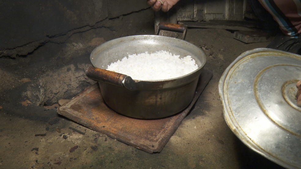 Arroz cozinhando em fogão improvisado no chão — Foto: Reprodução/TV Globo
