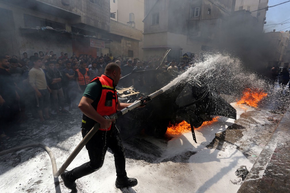 Membro da Defesa Civil Palestina apaga incêndio em carro do comandante do Hamas morto neste domingo (5) em Gaza — Foto: Ashraf Abu Amrah/Reuters