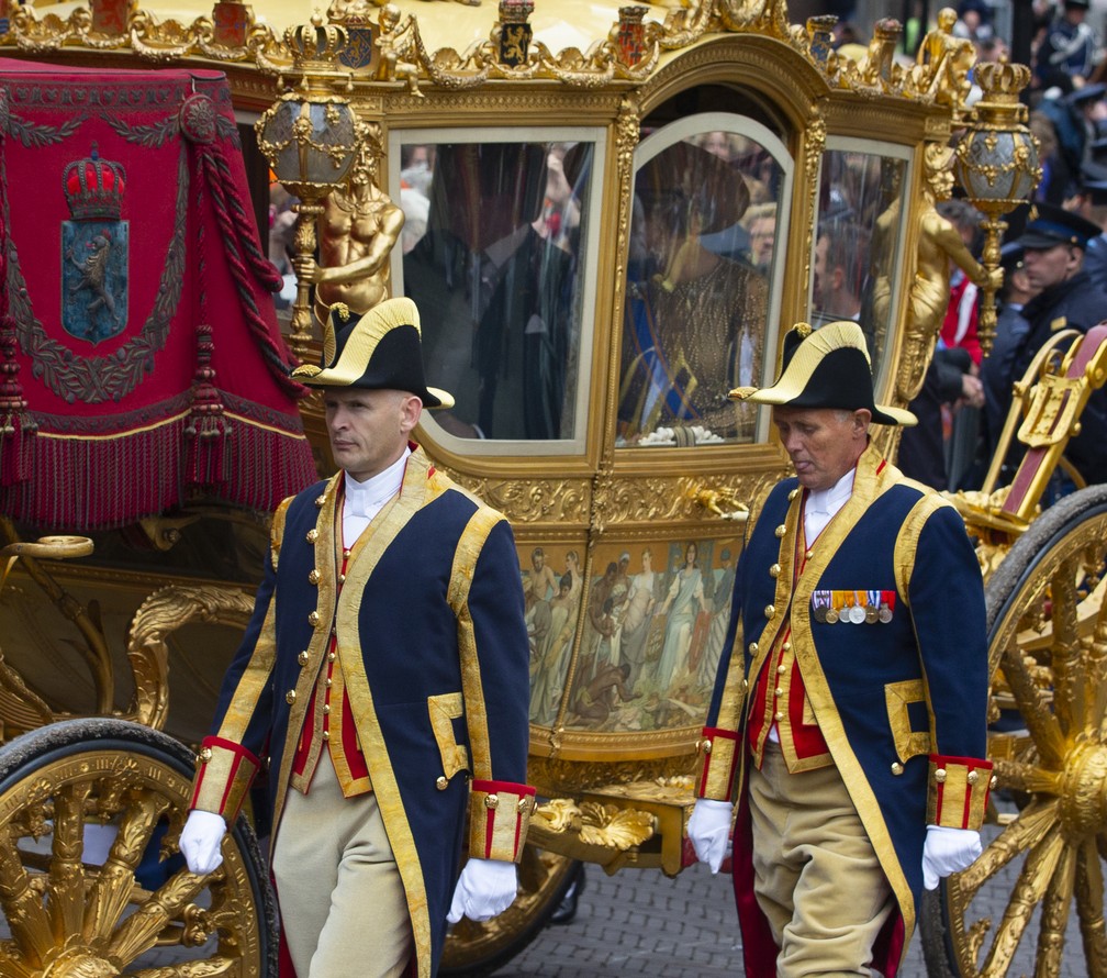 Lacaios caminham ao lado da Carruagem Dourada, que leva o rei Willem-Alexander e a rainha Maxima ao Palácio Noordeinde, após o rei da Holanda abrir oficialmente o ano parlamentar em Haia, Holanda, em 17 de setembro de 2013 — Foto: Peter Dejong/AP