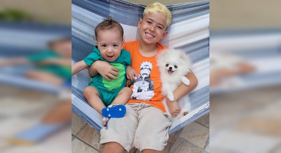 Os irmãos Gustavo, de 8 anos, e Brunno, de 1, com o spitz alemão Carlos  — Foto: Arquivo pessoal/Juliana Coutinho