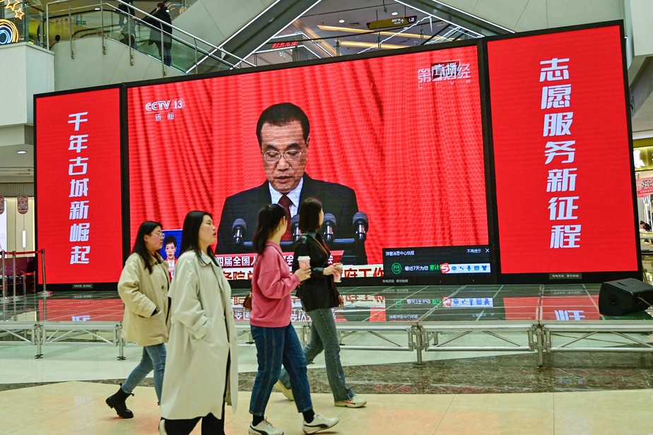 Cidadãos assistem à abertura do Congresso Nacional do Povo (CNP) em um shopping em Qingzhou, na China