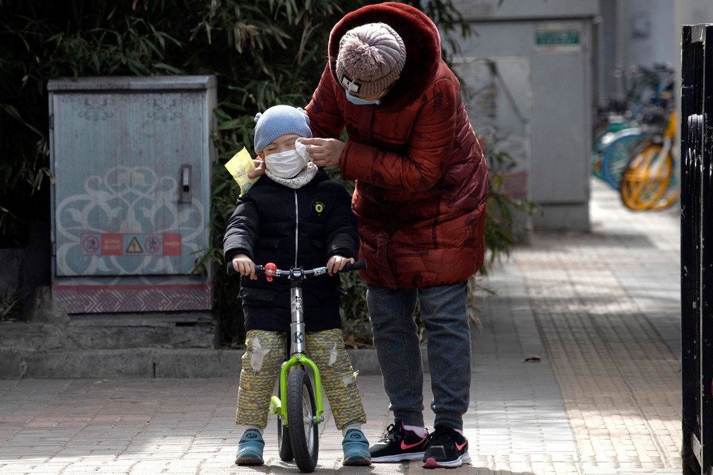 Mulher limpa o rosto de uma criança com um lenço nas ruas de Pequim, na China, nesta quinta-feira (12)  — Foto: Han Han Guan/AP