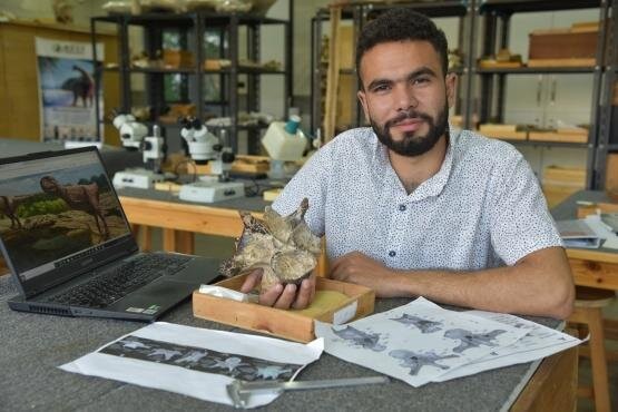 Belal Salem, líder do estudo, da Universidade de Ohio e do Centro de Paleontologia de Vertebrados da Universidade de Mansoura, no Egito, examina a vértebra do pescoço de terópode abelisaurídeo de aproximadamente 98 milhões de anos (Foto: Universidade de Ohio )