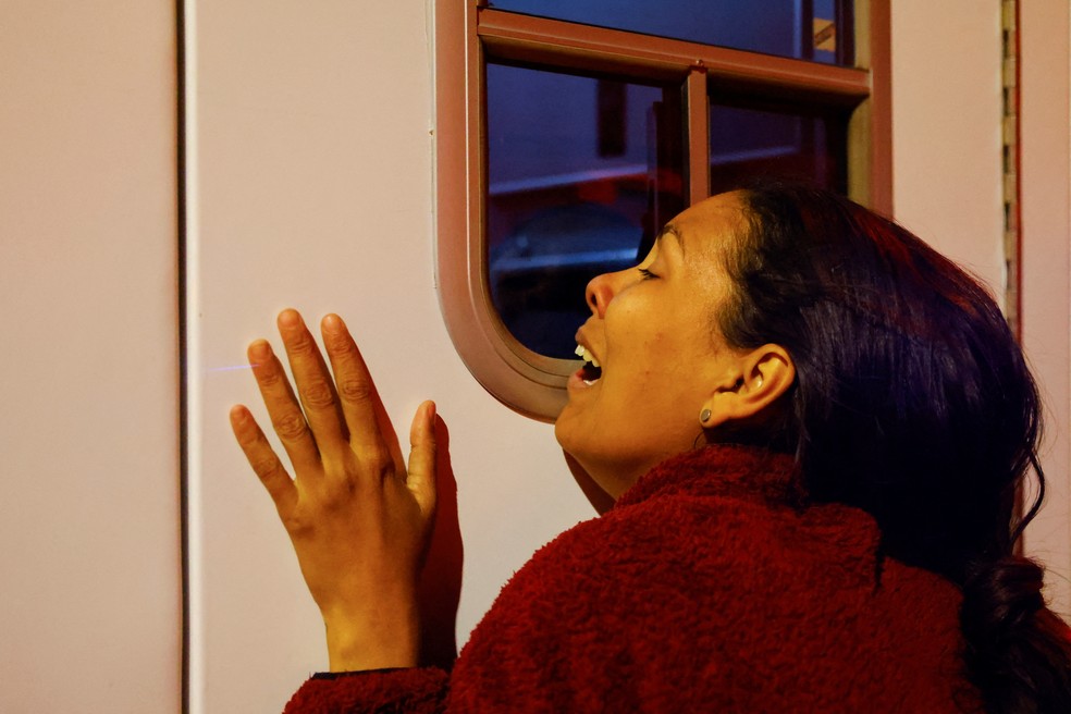 Mulher chora em porta de ambulância na cidade de Juarez, no México em 28 de março de 2023 — Foto: Jose Luis Gonzalez/REUTERS