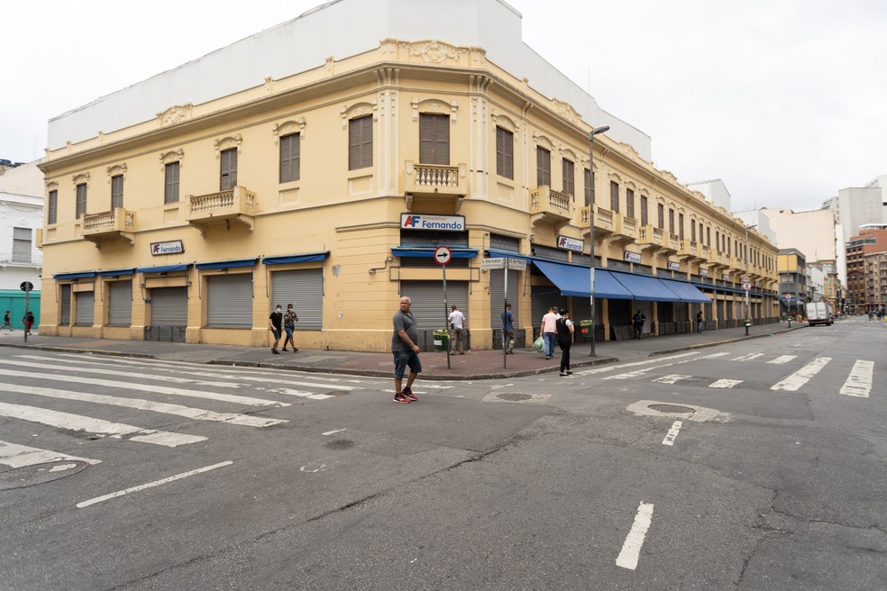 Pessoas passam pela rua 25 de mar&ccedil;o, em S&atilde;o Paulo, com o com&eacute;rcio fechado no in&iacute;cio da quarentena. &mdash; Foto: Marcelo Brandt/G1