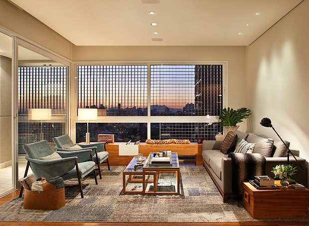 Vista do pôr-do-sol na sala de estar bem moderna, com iluminação e décor aconchegantes  (Foto: MCA Estúdio)