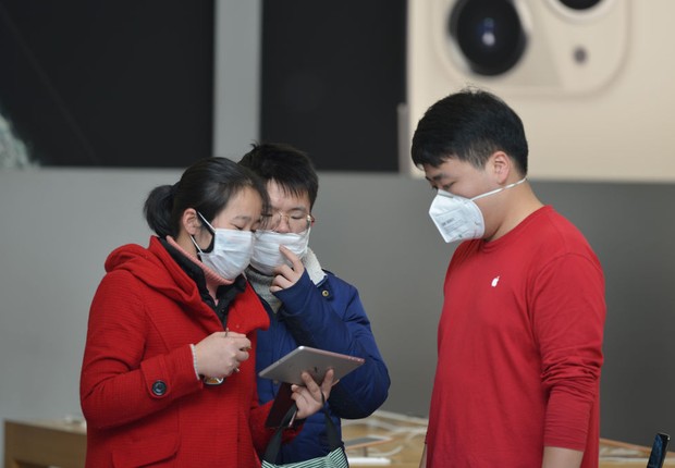 Uma equipe mascarada aguarda dois clientes verificando um iPad em uma Apple Store em Nanjing, na província de Jiangsu, leste da China (Foto:  Barcroft Media / Colaborador via Getty Images)