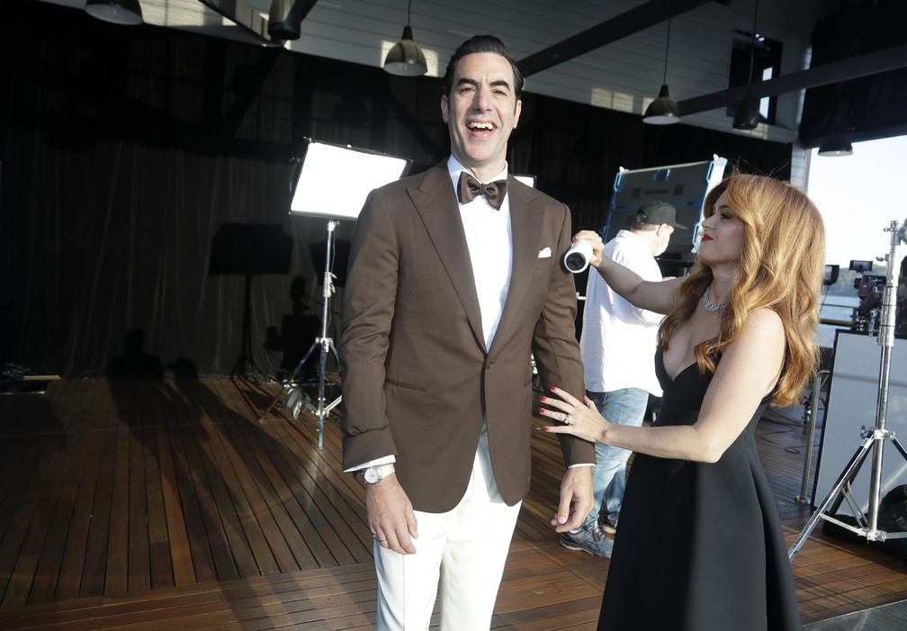 Isla Fisher ajuda Sacha Baron Cohen com os ajustes finais para a sessão de fotos para o Oscar; casal participou da cerimônia direto da Austrália — Foto: AP Photo/Rick Rycroft