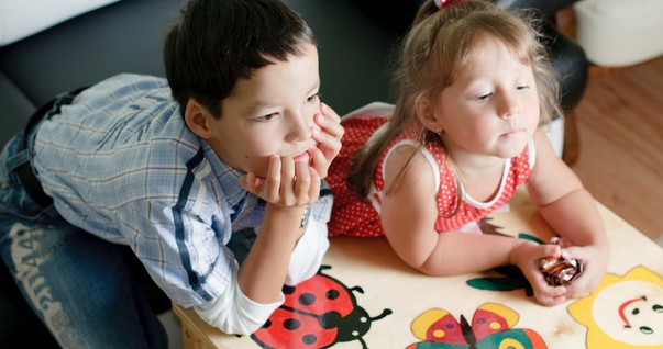 Crianças apoiadas na mesa assistindo televisão (Foto: Shutterstock)