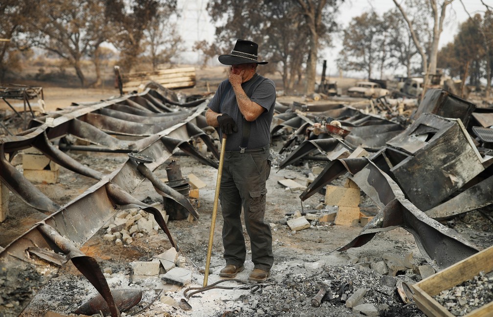 Ed Bledsoe tenta segurar as lágrimas enquanto procura pelo que restou de sua casa, em Redding, na Califórnia. A esposa de Bledsoe, Melody, o bisneto James Roberts e a bisneta Emily Roberts foram mortos no local durante incêndios florestais (Foto: John Locher/AP)