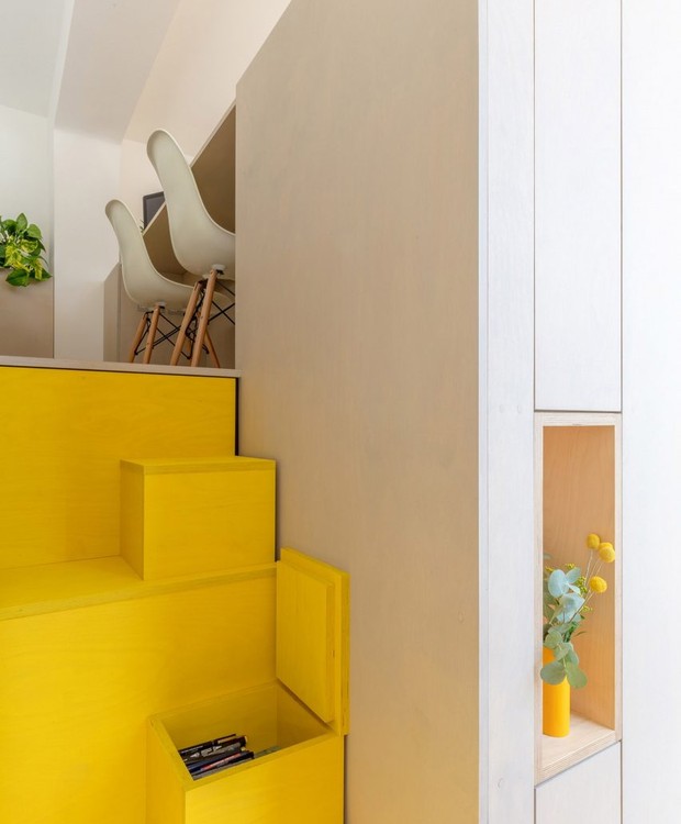 A escada é o único ponto de cor além da madeira. Colorida em amarelo, ela conta com caixinhas que formam compartimentos (Foto: Dezeen/ Reprodução)