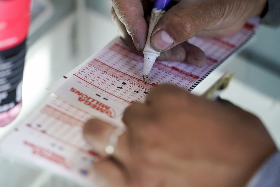 Homem escreve em cartela da Mega Million os números que deseja para concorrer ao sorteio — Foto: Godofredo A. Vásquez/AP